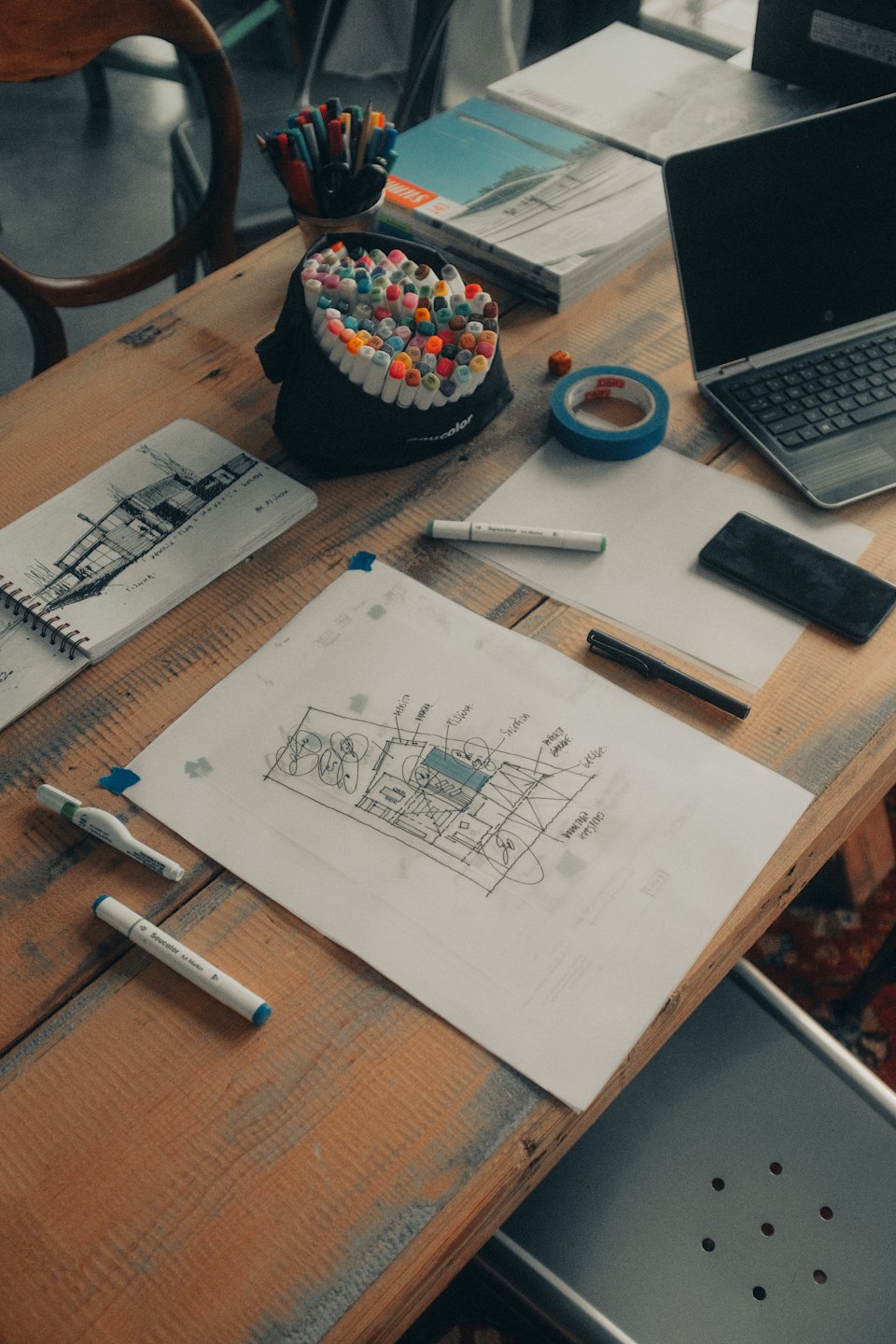 Architectural sketches and colorful markers on a busy desk.