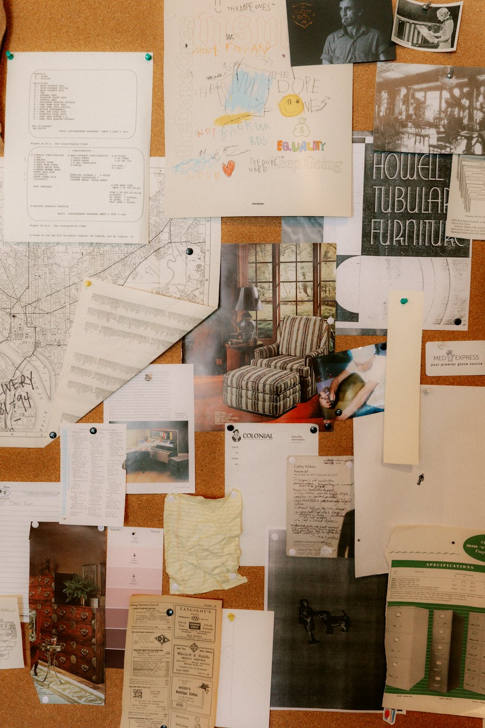 Cork bulletin board covered with various pinned documents and drawings.