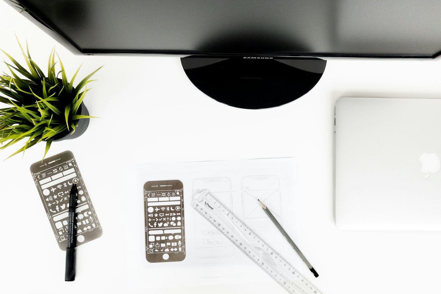 Designer's desk with laptop, monitor, and sketching tools.